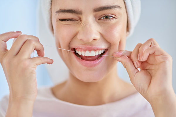 Eine junge Frau benutzt Zahnseide